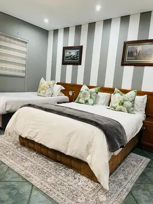 two beds in a room with striped walls at Pari Guest House in Middelburg