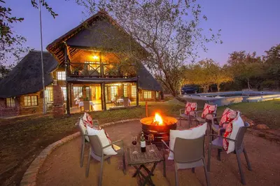 a group of chairs and a fire pit in front of a house at Imbube Safari Lodge in Marloth Park
