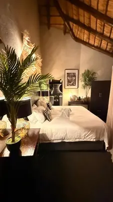 a bedroom with a bed with a plant on a table at Imbube Safari Lodge in Marloth Park