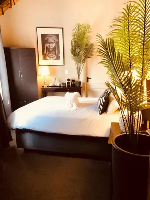 a bedroom with a large bed with plants in it at Imbube Safari Lodge in Marloth Park