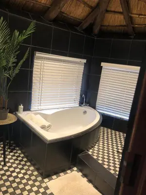 a bath tub in a bathroom with two windows at Imbube Safari Lodge in Marloth Park