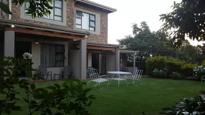 a table and chairs in the yard of a house at Sunbird Garden Cottage in Pretoria