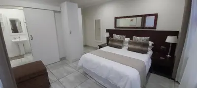 a bedroom with a large bed and a mirror at Sunbird Garden Cottage in Pretoria