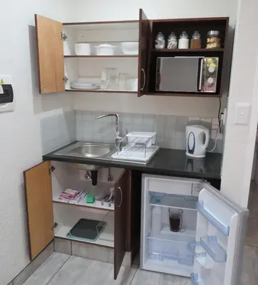 a small kitchen with a sink and a refrigerator at Sunbird Garden Cottage in Pretoria