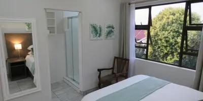 a bedroom with a bed and a mirror and a window at Sunbird Garden Cottage in Pretoria