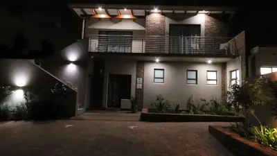 a house lit up at night with a balcony at Sunbird Garden Cottage in Pretoria