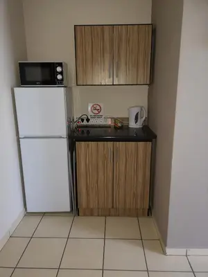 a small kitchen with a refrigerator and a microwave at AAA Rose Garden Guesthouse in Naboomspruit
