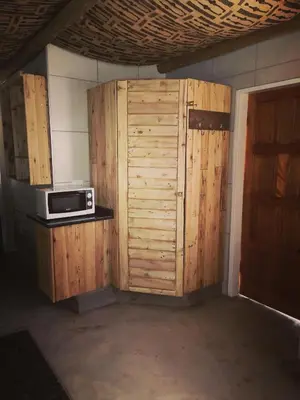 a kitchen with a microwave and a wooden wall at AAA Rose Garden Guesthouse in Naboomspruit