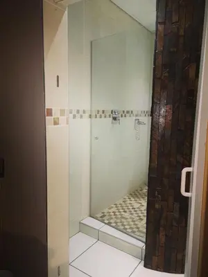 a shower with a glass door in a bathroom at AAA Rose Garden Guesthouse in Naboomspruit