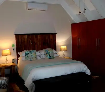 a bedroom with a large bed with a wooden headboard at The Leopard Tree in Polokwane