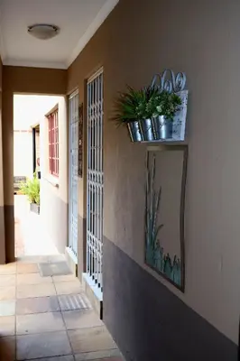 a hallway with a mirror and plants on the wall at The Leopard Tree in Polokwane