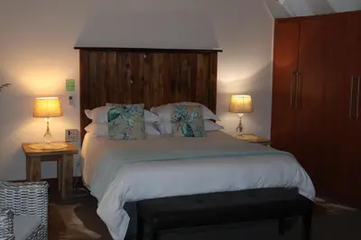 a bedroom with a large bed with two lamps at The Leopard Tree in Polokwane