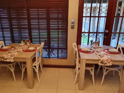 a dining room with two tables and chairs and windows at The Leopard Tree in Polokwane