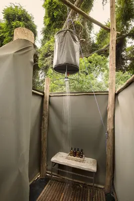 a hanging hammock with shoes on a bench on a porch at Nkula Walking Camp by RETURN Africa in Makuleke Contract Park