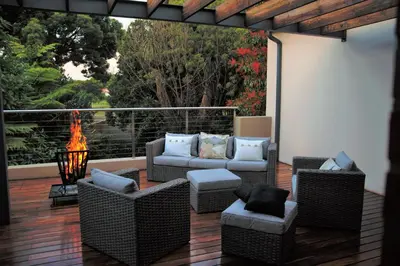 a patio with wicker chairs and a fire place at Hudson House in Pretoria