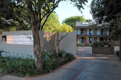 a sign in front of a building with a tree at Hudson House in Pretoria