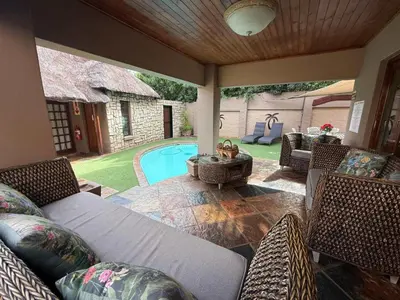 a patio with a couch and chairs and a pool at The Orion Guesthouse in Middelburg