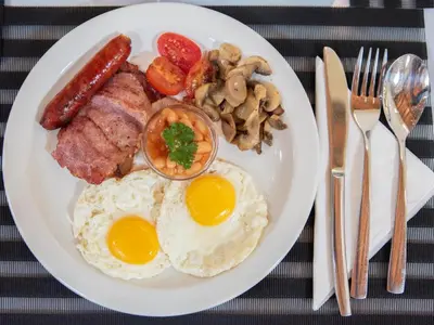 a plate of breakfast food with eggs sausage and mushrooms at The Orion Guesthouse in Middelburg