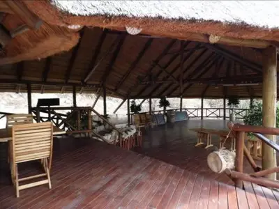 a large straw roofed pavilion with a table and chairs at Sunset Creek Game Lodge in Karino