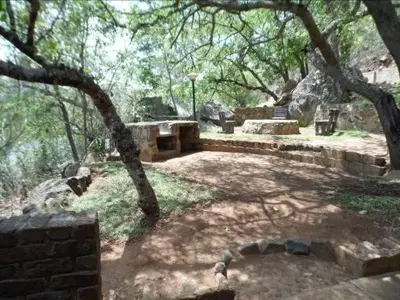 a park with trees and rocks and a stone patio at Sunset Creek Game Lodge in Karino