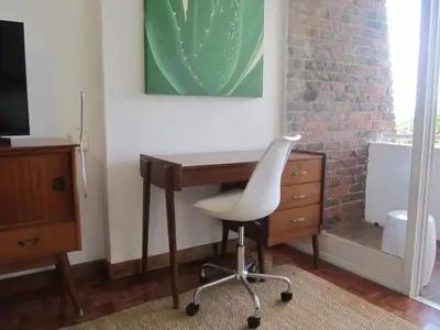 a desk with a white chair next to a dresser at House Sandrock Muckleneuk Selfcatering apartment in Pretoria