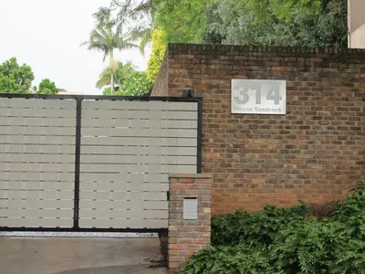a brick wall with a sign that reads at House Sandrock Muckleneuk Selfcatering apartment in Pretoria