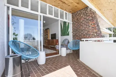 a patio with blue chairs and a brick wall at House Sandrock Muckleneuk Selfcatering apartment in Pretoria