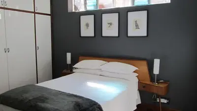 a bedroom with a bed with three pictures on the wall at House Sandrock Muckleneuk Selfcatering apartment in Pretoria