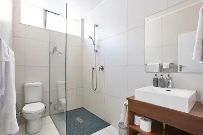 a bathroom with a shower and a toilet and a sink at House Sandrock Muckleneuk Selfcatering apartment in Pretoria