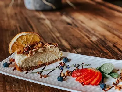 a piece of cake on a plate with strawberries and blueberries at Godiva Spa & Guesthouse in Groblersdal