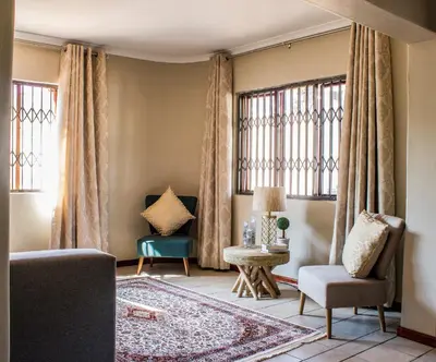 a living room with a couch and chairs and windows at Pro Active Guest House in Pretoria