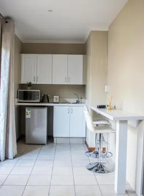 a kitchen with white cabinets and a white counter top at Pro Active Guest House in Pretoria