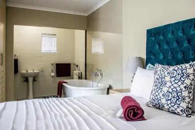 a bedroom with a bed and a tub and a sink at Pro Active Guest House in Pretoria