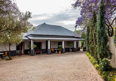 a building with a black roof and a brick driveway at Pro Active Guest House in Pretoria