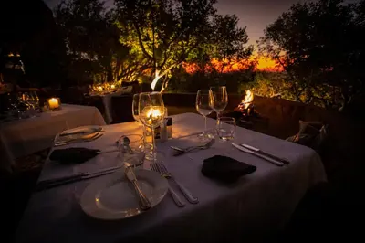 a table set with wine glasses and napkins with a sunset at Nedile Lodge in Welgevonden Game Reserve