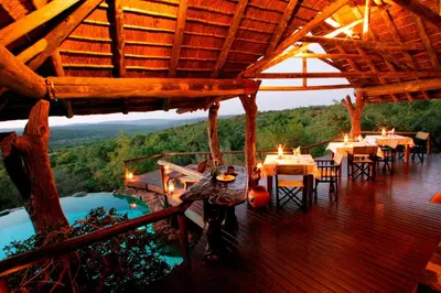 a restaurant with tables and chairs on a deck at Nedile Lodge in Welgevonden Game Reserve
