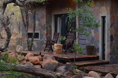 a porch of a stone house with chairs and rocks at Kukama's Rest at Zebula 317 in Mabula