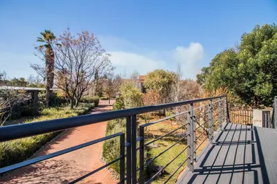 a metal bridge over a dirt road with trees at Craigivar Guesthouse in Pretoria