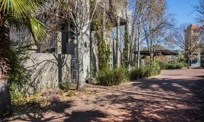 a tree next to a house with a sidewalk at Craigivar Guesthouse in Pretoria
