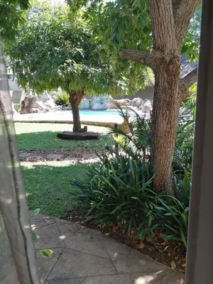 a view of a yard with trees and a swimming pool at Guinea Feather Country Lodge & Spa in Groblersdal