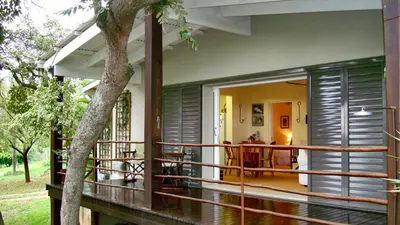 a house with a balcony with a table on it at umSisi Cottage in White River