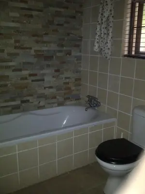 a bathroom with a toilet and a bath tub with a black seat at 42onKing in Centurion