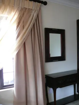 a window with a curtain and a mirror and a table at 42onKing in Centurion