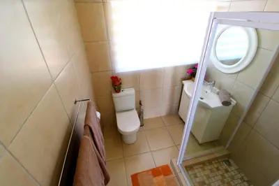 a bathroom with a toilet and a sink and a mirror at Wilger Guesthouse in Centurion