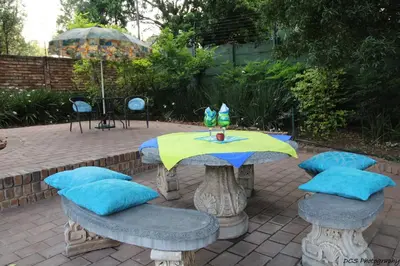 a patio table with blue pillows and an umbrella at Wilger Guesthouse in Centurion