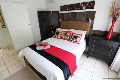 a bedroom with a bed with a red blanket and pillows at Wilger Guesthouse in Centurion