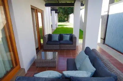 a porch with two couches and a glass table at Graskop Harrie's Cottage in Graskop