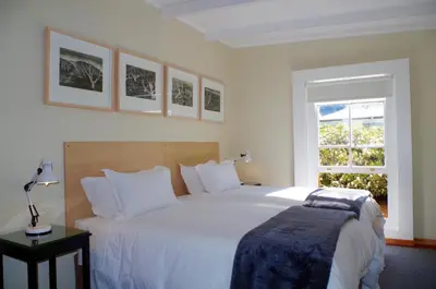 a bedroom with a large white bed and a window at Graskop Harrie's Cottage in Graskop