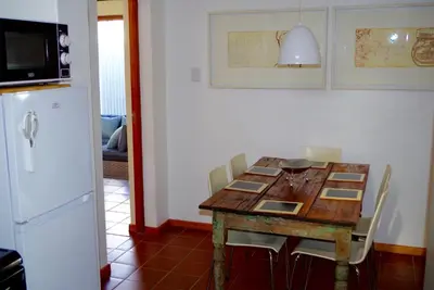 a kitchen with a wooden table with chairs and a refrigerator at Graskop Harrie's Cottage in Graskop