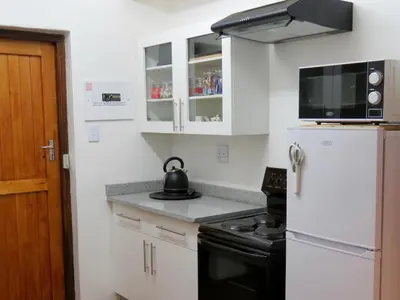 a kitchen with a white refrigerator and a tea kettle at Graskop Harrie's Cottage in Graskop